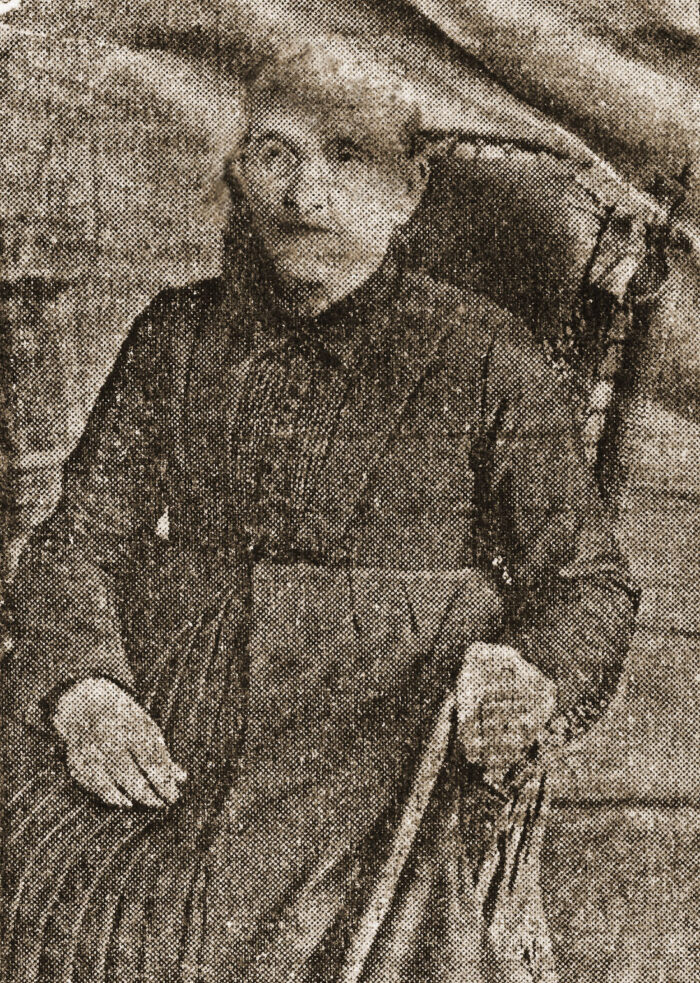 Vintage sepia portrait of a woman in a high-collared, long-sleeved dress seated with her hands resting on her lap.