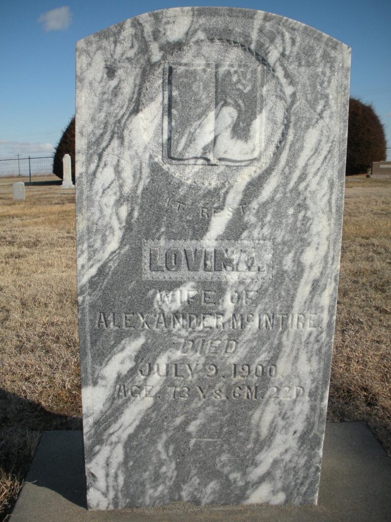 Marble tombstone with gray veining in a cemetery; reads 'Loving wife of Alexander McIntire' and 'Died July 9, 1900'.