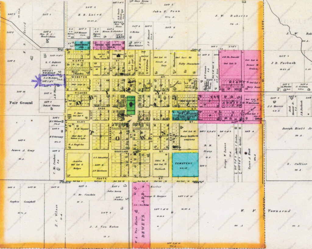 Historic map showing a town with colored parcel blocks along streets; orange borders and a blue cemetery area visible in the lower portion.